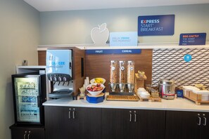 A breakfast station with a coffee machine, fruit and cereal dispensers, and a sign for Express Start Breakfast.
