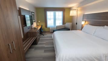 A hotel room with a bed, a desk, a chair, a television, and a window.