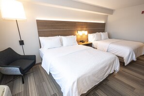Een hotelkamer met twee bedden, een bureau, een stoel en een lamp.