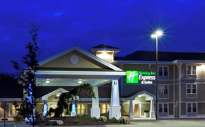A Holiday Inn Express & Suites with a covered entrance, a lighted sign, and a well-lit facade.