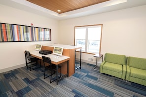A modern office space with a desk, two chairs, a green sofa, and a large window. - Holiday Inn Express Hotel & Suites Iron Mountain by IHG (Iron Mountain)