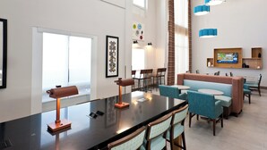 A modern hotel lobby with a long reception desk, seating area, and a large window. - Holiday Inn Express Hotel & Suites Scott - Lafayette West by IHG (Scott)