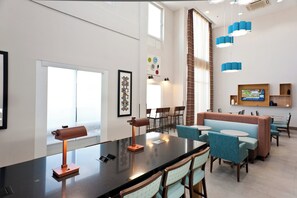 A modern hotel lobby with a long reception desk, seating area, and a large window. - Holiday Inn Express Hotel & Suites Scott - Lafayette West by IHG (Scott)