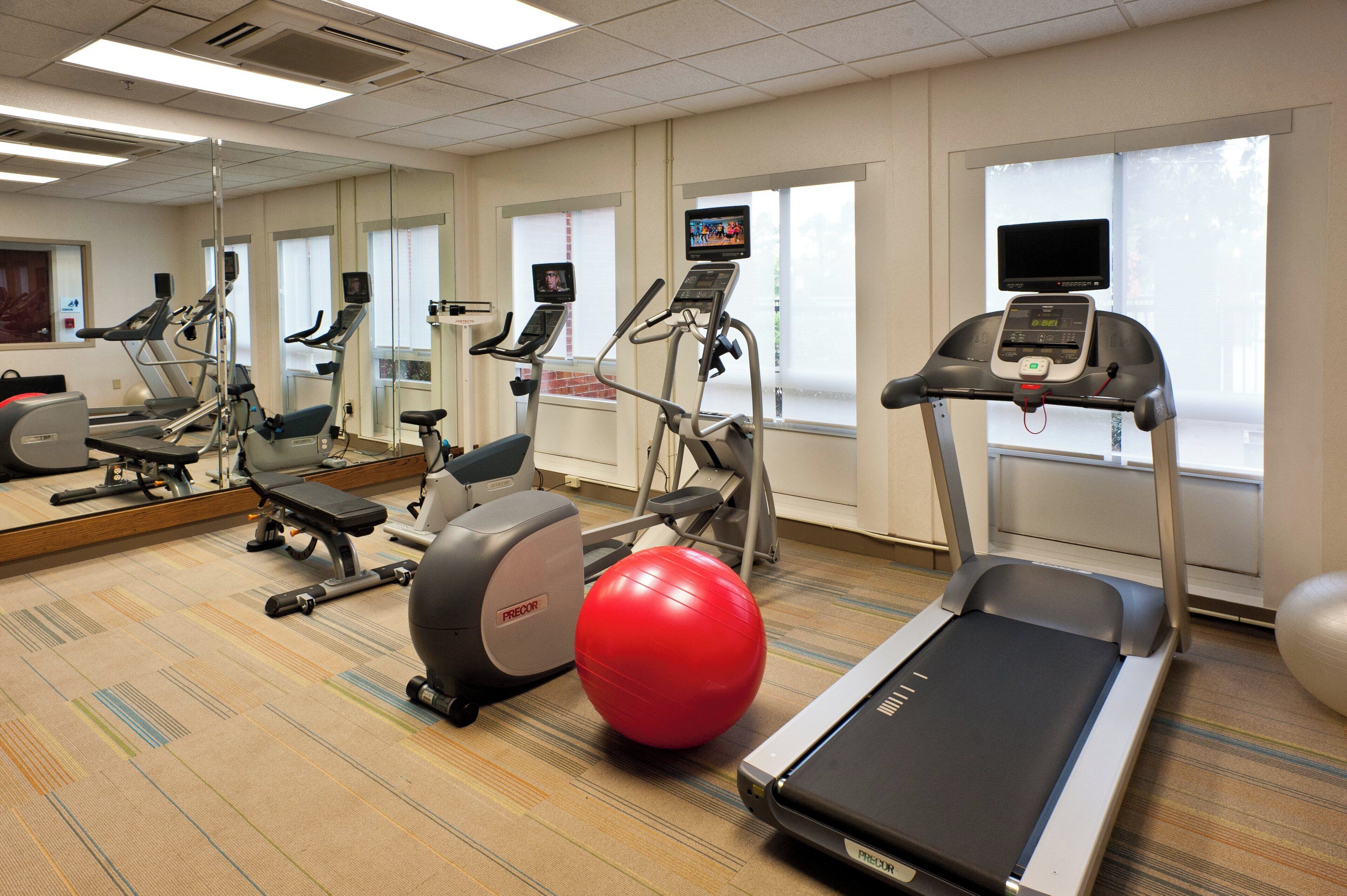 A gym with treadmills, stationary bikes, and exercise balls.