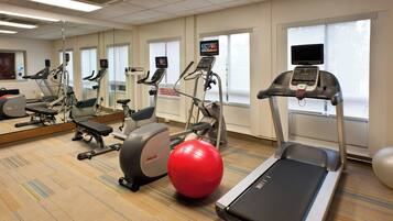 A gym with treadmills, stationary bikes, and exercise balls.