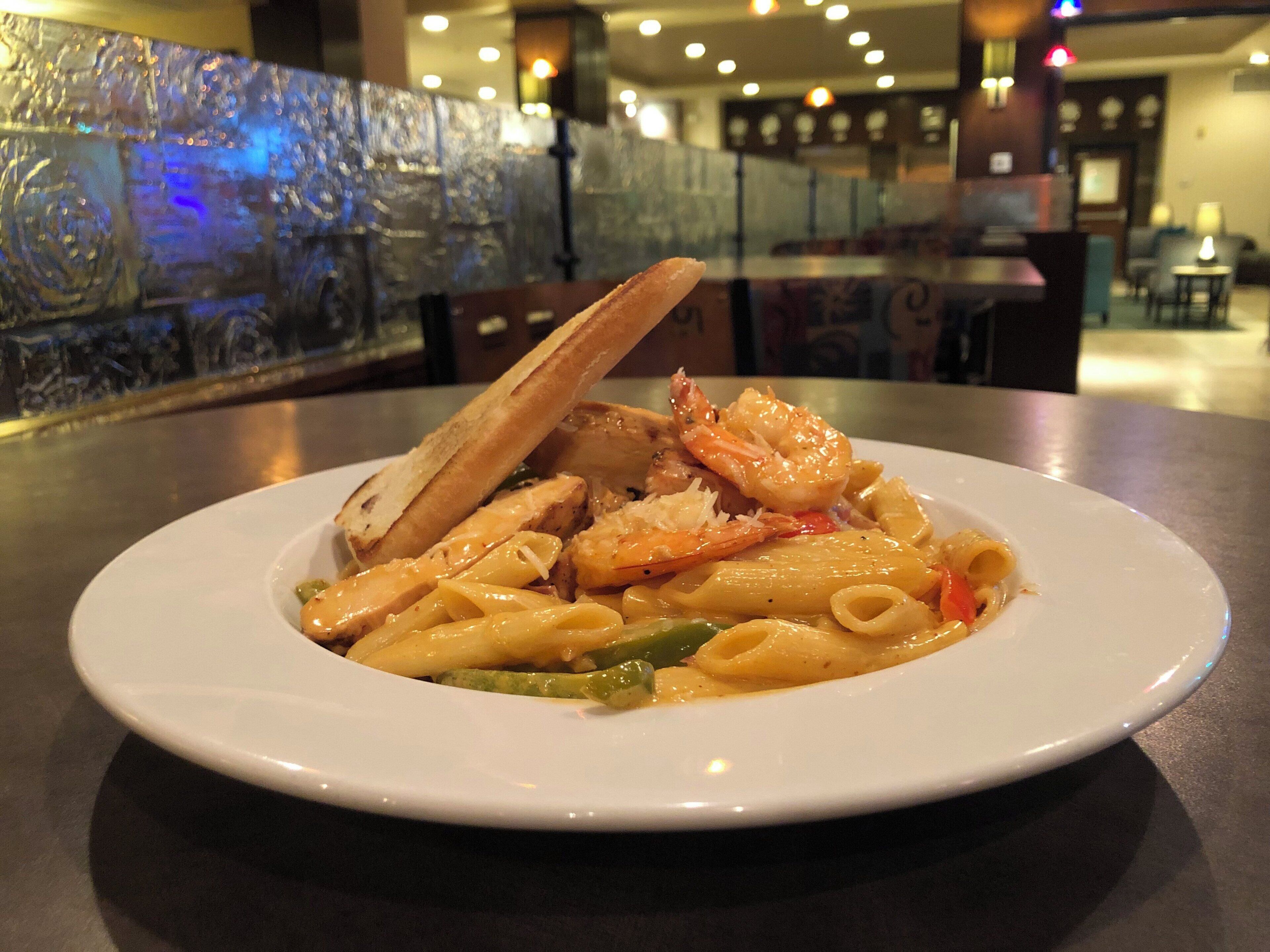 Un plato de pasta con camarones y pan sobre una mesa en un restaurante.
