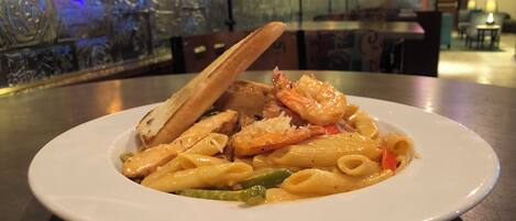 Un plato de pasta con camarones y pan sobre una mesa en un restaurante.