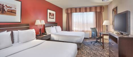 A hotel room with two beds, a desk with a chair, a television, and artwork on the walls.