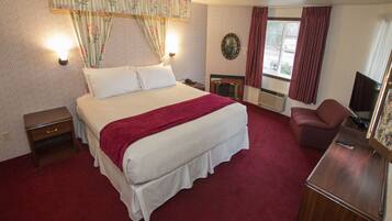 A hotel room with a large bed, a bedside table, a chair, a television, and a window with curtains.