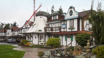 A traditional European-style building with a windmill, stone pathway, and a statue in the garden.