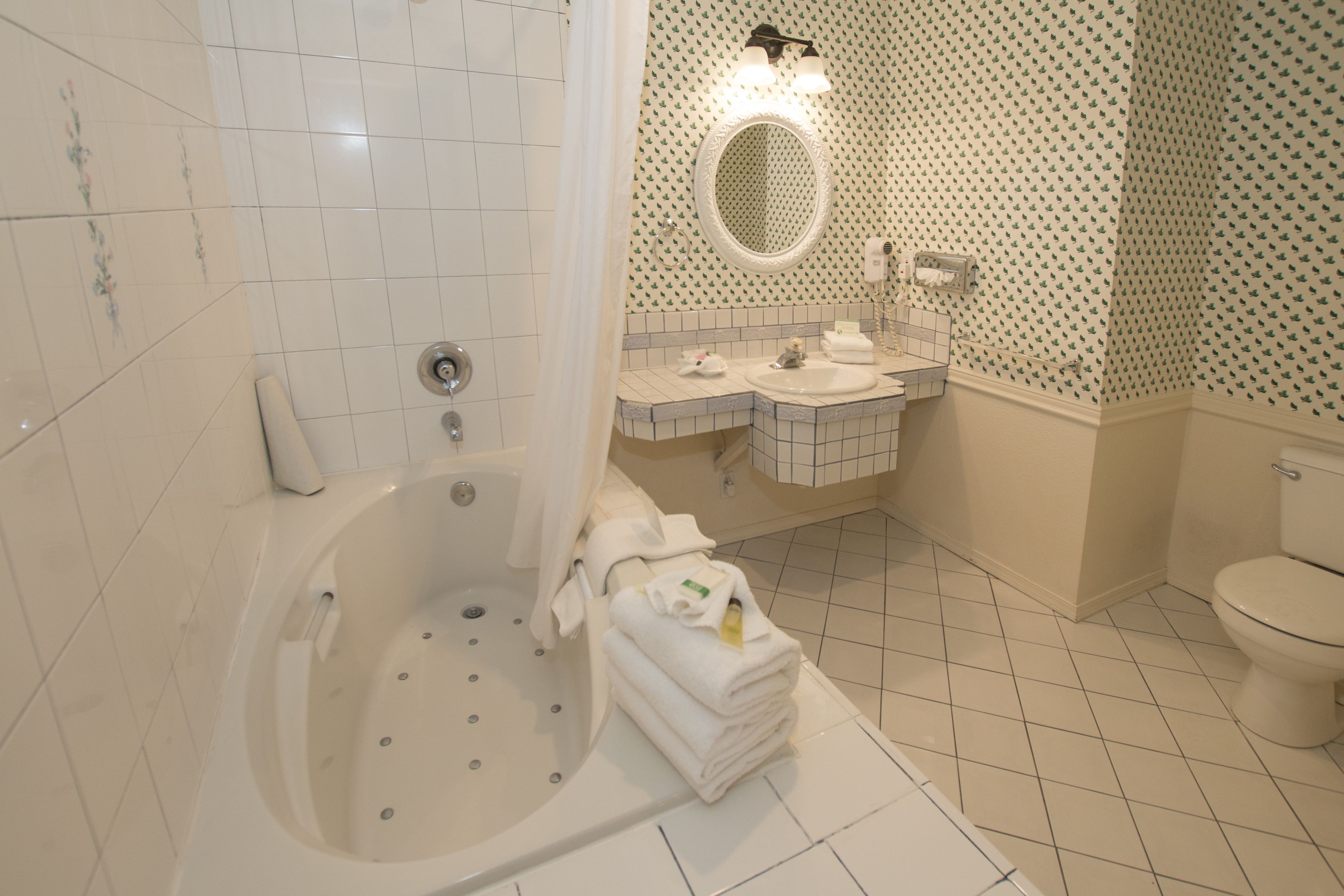 A bathroom with a bathtub, a sink, a toilet, and a mirror.