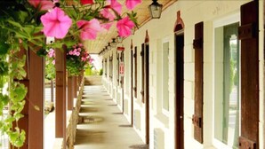 A corridor with a covered walkway, columns, and doors leading to rooms. - Auld Holland Inn (Oak Harbor)