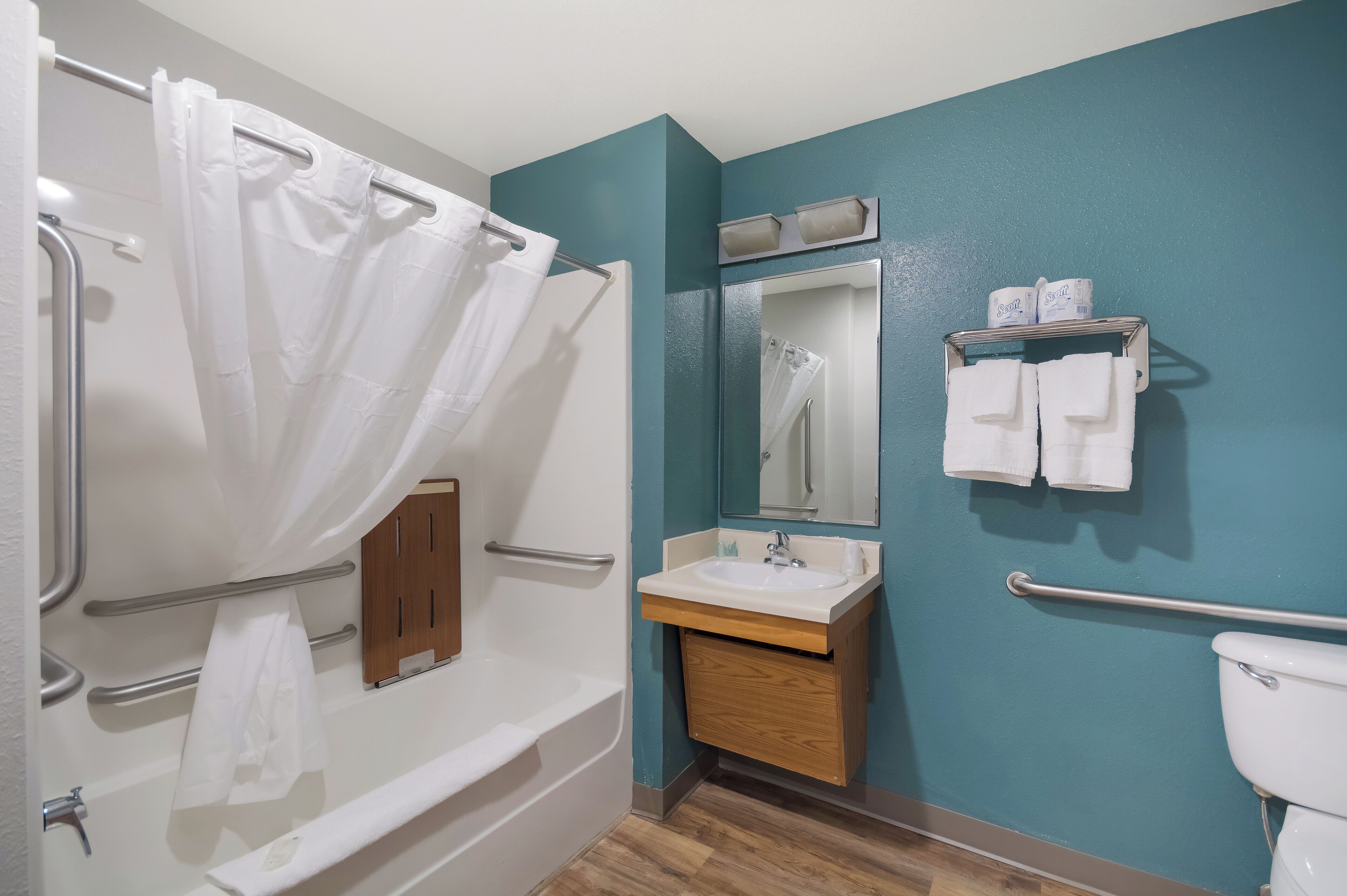 A bathroom with a bathtub, a sink, a mirror, and a toilet.