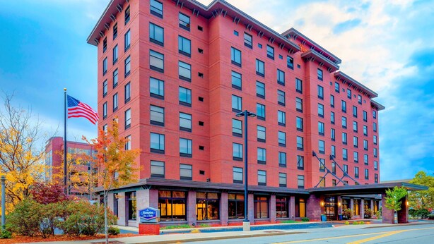 A multi-story hotel with a brick facade, large windows, and a flagpole with an American flag. - Hampton Inn & Suites Pittsburgh-Downtown (Pittsburgh)
