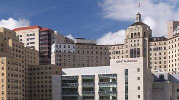 Un edificio histórico de varios pisos, con una destacada torre de reloj y un cartel que dice "UPMC Presbyterian".