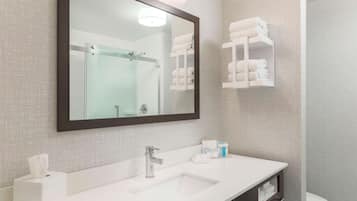 A modern bathroom with a large mirror, a white sink, and a glass shower enclosure.