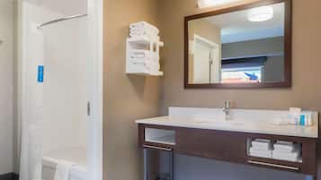 A bathroom with a shower, a sink with a mirror, and towel storage.