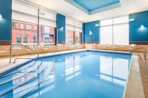 Una piscina con sillas y vistas a un edificio de ladrillo rojo.