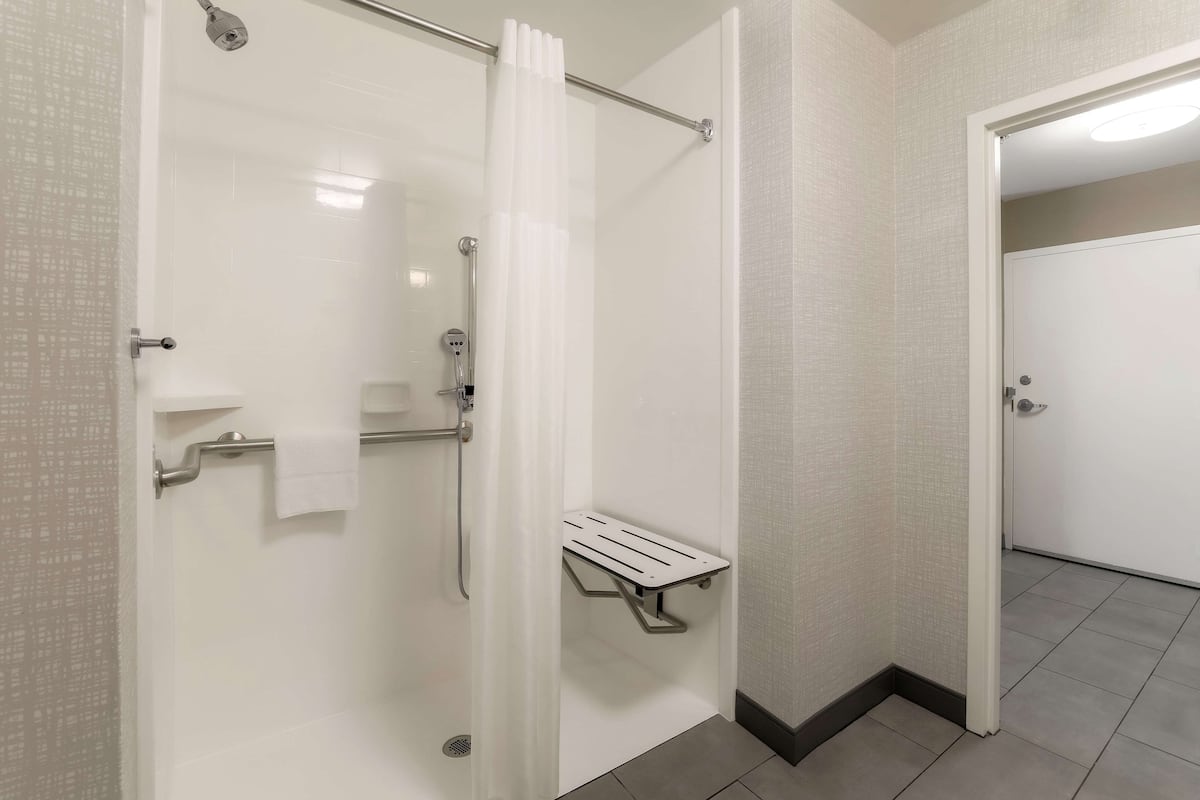 Um banheiro moderno com box de vidro, porta-toalhas branco e prateleira de metal.