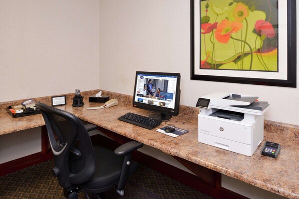 A hotel office desk with a computer, printer, and phone.