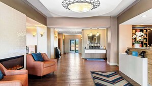 Vestíbulo de hotel con chimenea, sofás, un mostrador de recepción y vistas al exterior.