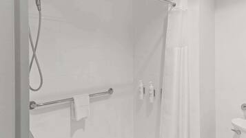 Uma casa de banho moderna com cabine de duche em vidro, porta-toalhas e produtos de higiene pessoal na parede.