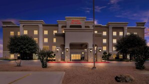 Un hotel con fachada moderna, entrada destacada y camino de acceso bien iluminado.