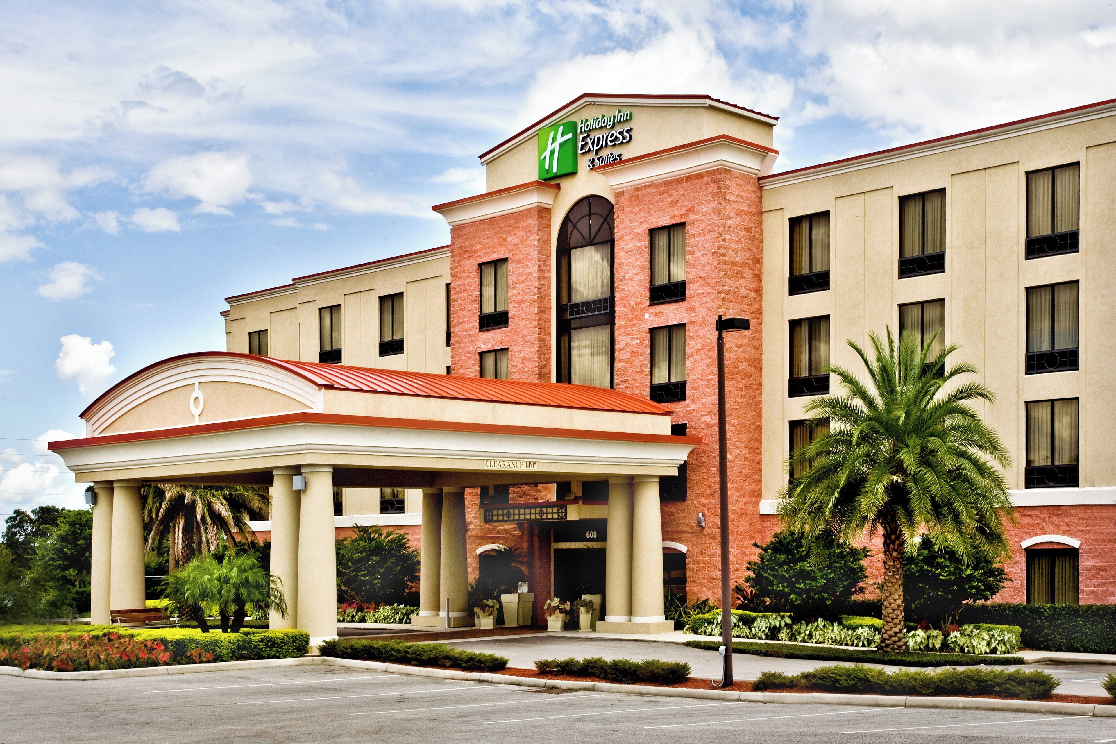 Edificio de Holiday Inn Express con entrada cubierta, señalización clara y un jardín delantero ajardinado.