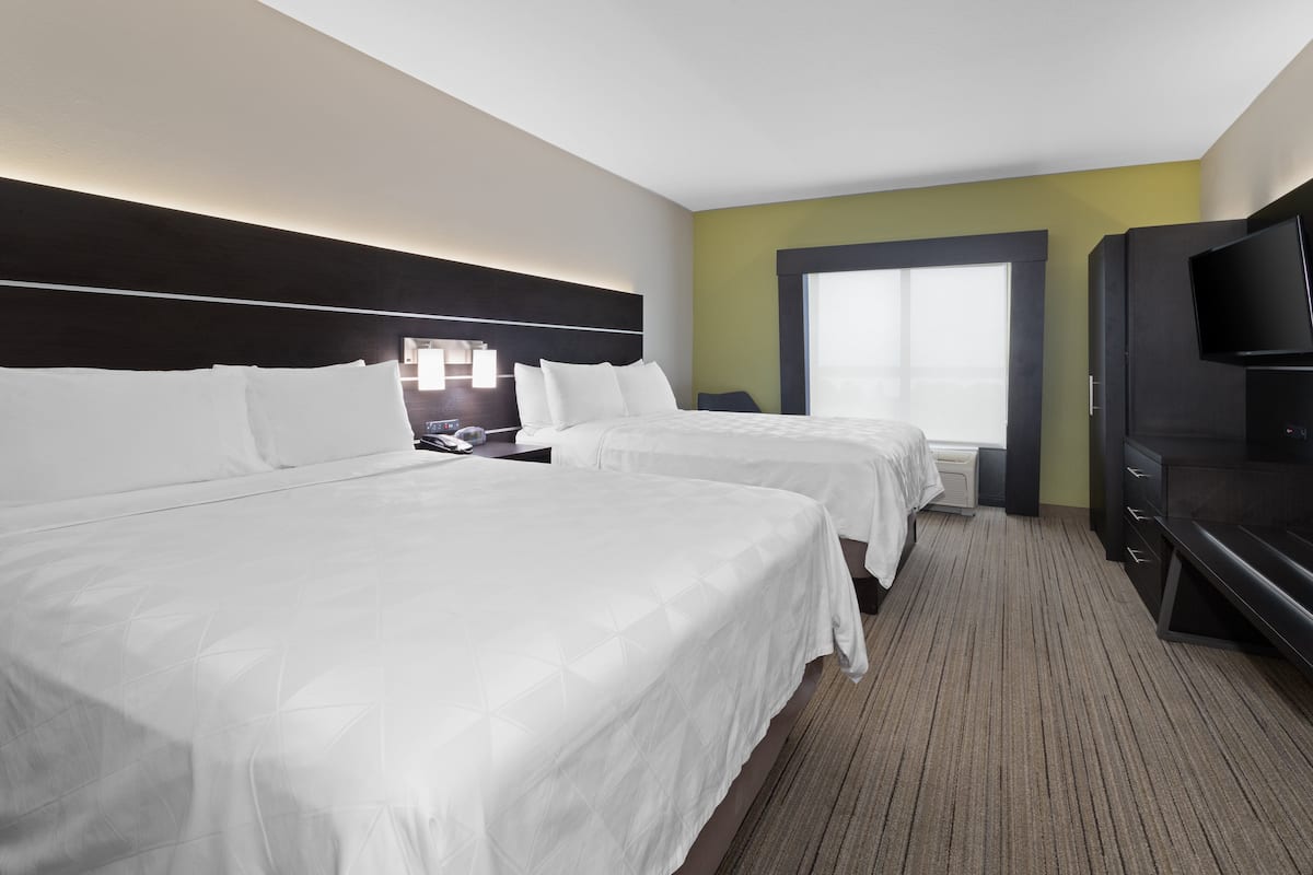 Habitación de hotel con dos camas, televisión, escritorio y ventana.