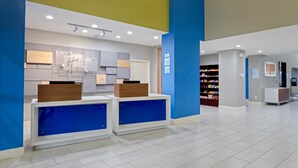 A reception area with two blue counters, a wooden reception desk, and a wall-mounted information board.