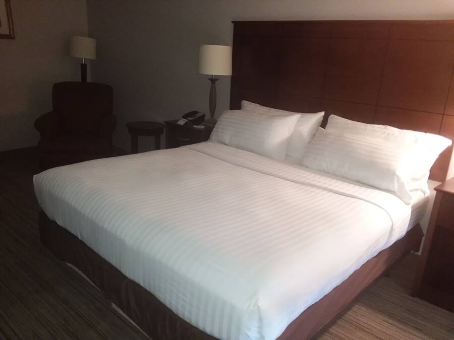 Une chambre d’hôtel avec un grand lit, deux tables de chevet, une chaise et deux lampes.