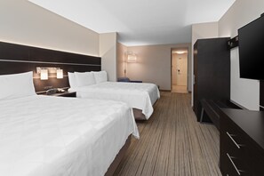 Une chambre d’hôtel avec deux lits, un téléviseur à écran plat, un bureau avec une lampe et un sol recouvert de moquette.