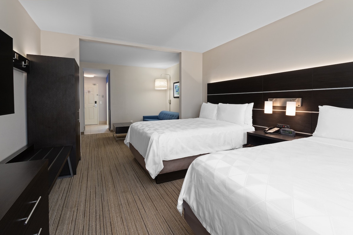 Habitación de hotel con dos camas, un escritorio y una televisión.