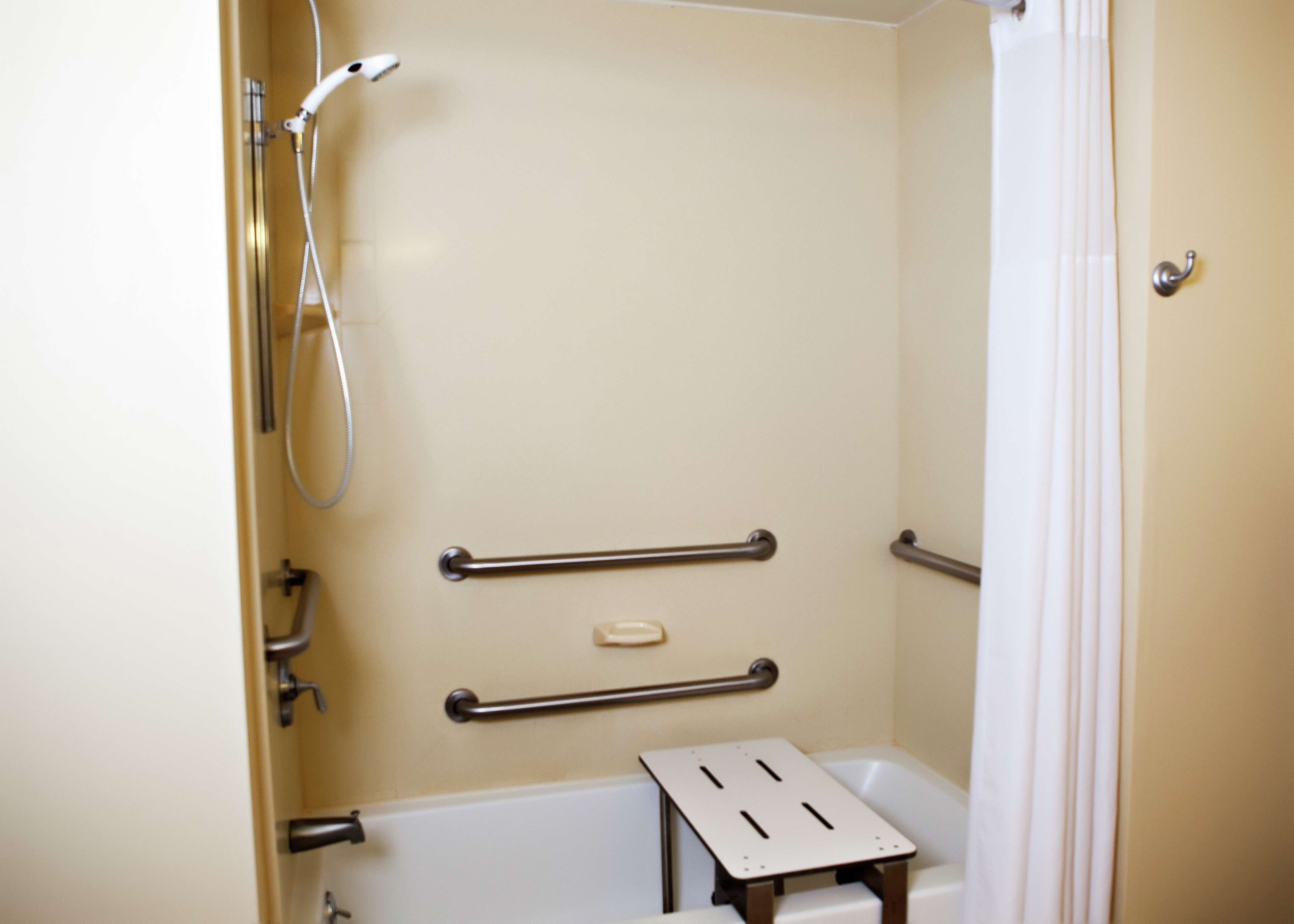 A bathroom with a bathtub, a shower, and grab bars.
