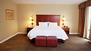 A hotel room with a large bed, two bedside tables with lamps, a framed picture on the wall, and a window with curtains.
