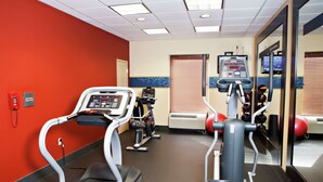 Un gimnasio con cintas de correr, elípticas y una máquina de remo.
