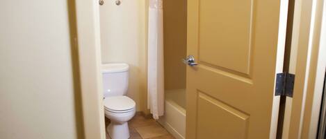 Een badkamer met een toilet, een douchegordijn en een deur.