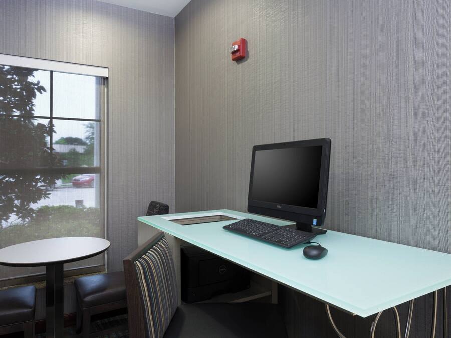 A modern office space with a glass desk, a computer, and a chair.