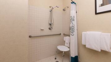 Ein Badezimmer mit Dusche, Haltegriff, Toilette und Handtuchhalter.