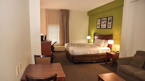A hotel room with a bed, a desk, a chair, a sofa, and a lamp. - Sleep Inn & Suites Laurel near Fort Meade (Laurel)