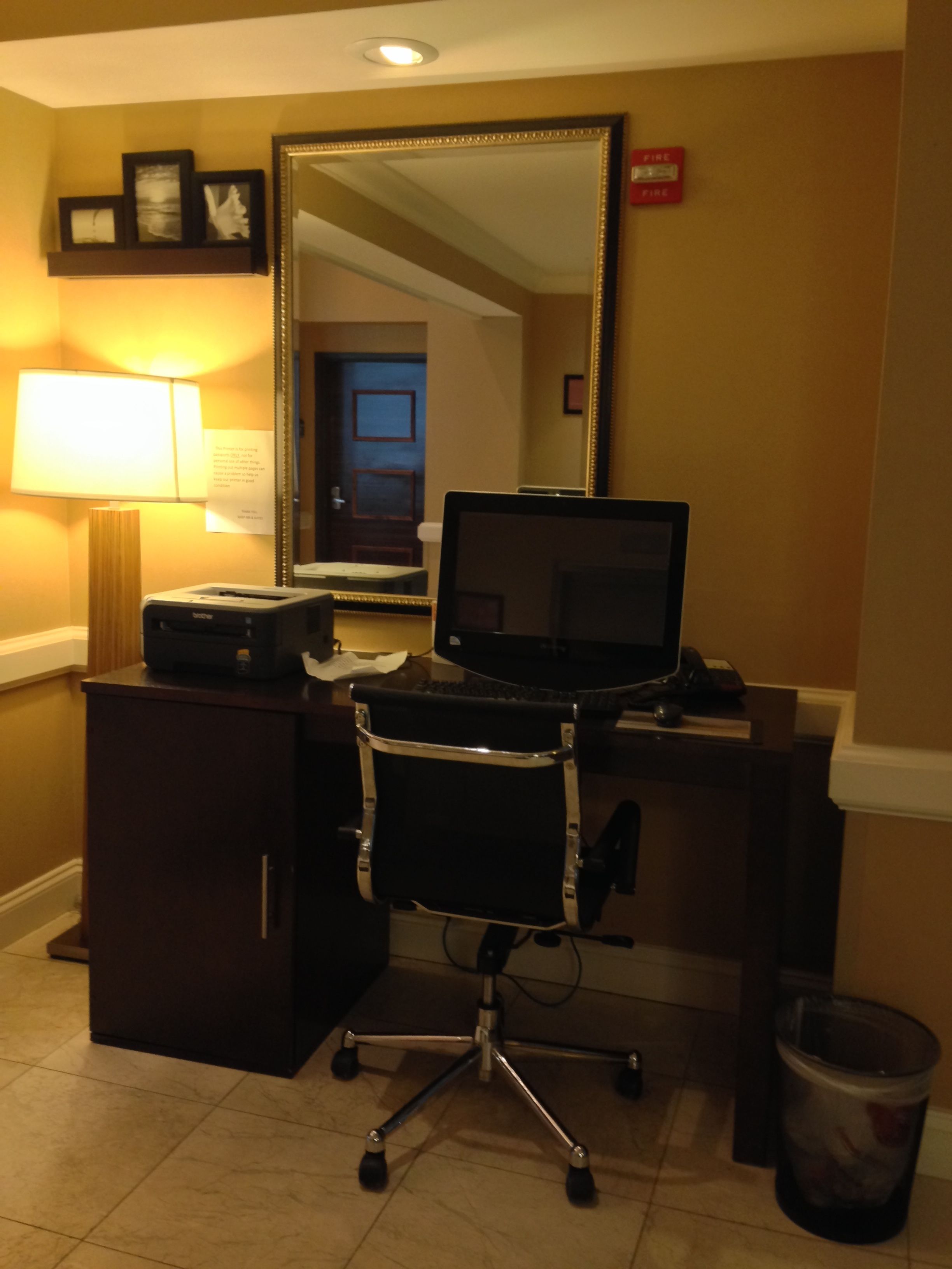 Une chambre d’hôtel équipée d’un bureau, d’une chaise, d’un ordinateur, d’une lampe et d’une poubelle.