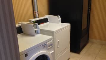 Une buanderie équipée d’un lave-linge et d’un sèche-linge à chargement frontal, d’un panneau de commande et d’un réfrigérateur noir.