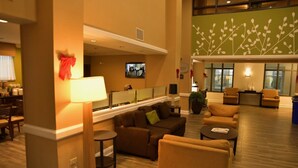 A spacious lobby with a sofa set, a coffee table, and a TV mounted on the wall. - Sleep Inn & Suites Laurel near Fort Meade (Laurel)