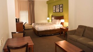 A hotel room with a bed, a wooden desk, a chair, a sofa, and a dining table. - Sleep Inn & Suites Laurel near Fort Meade (Laurel)