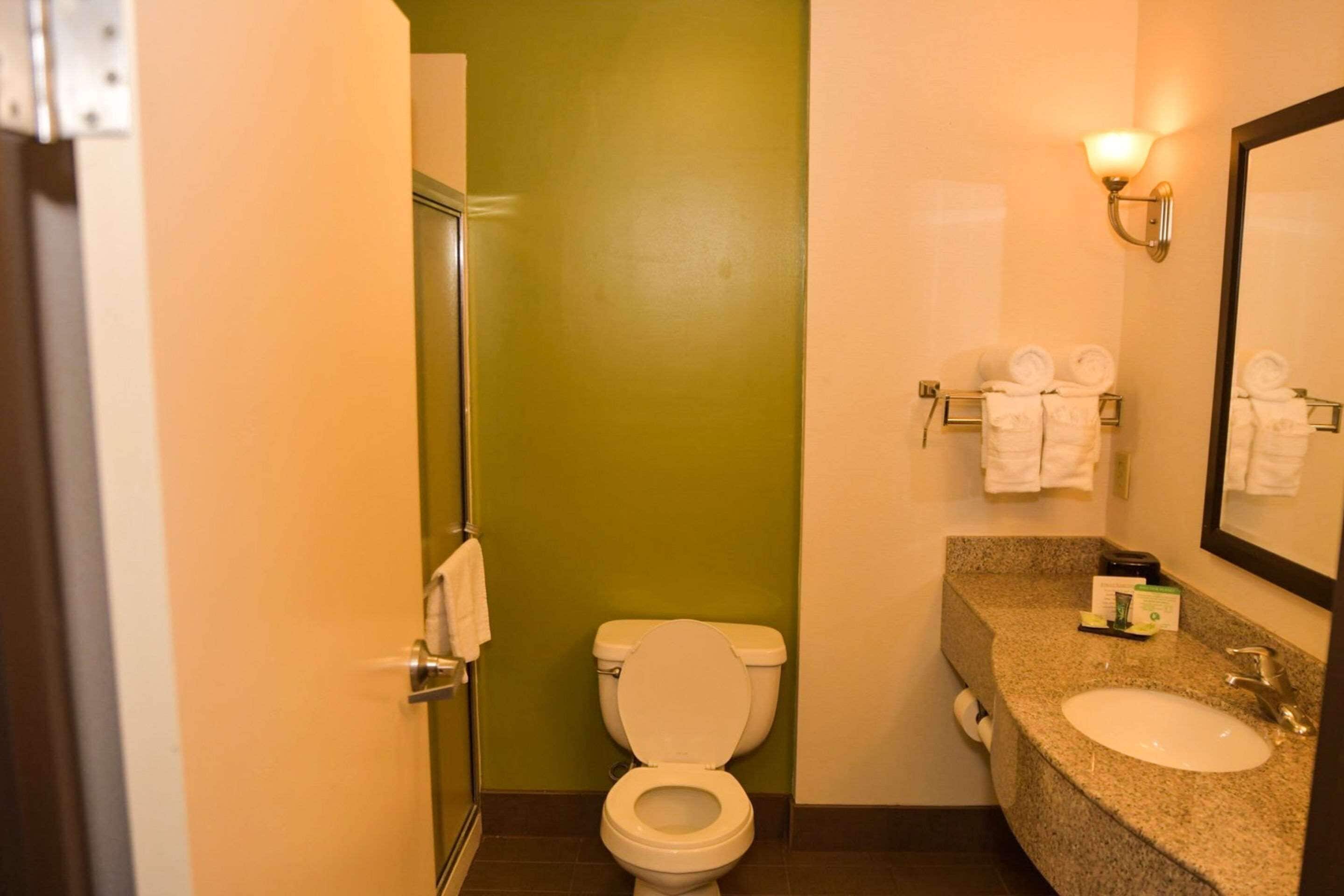 A bathroom with a white toilet, a sink, a mirror, and a towel rack with towels.