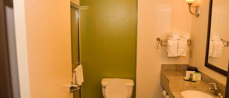 Une salle de bain avec des toilettes blanches, un lavabo, un miroir et un porte-serviettes avec des serviettes.