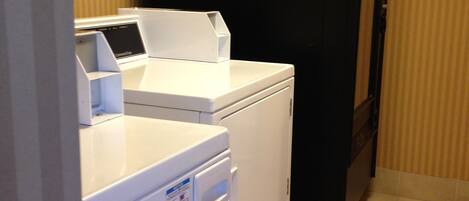 A laundry area with a front-loading washer and dryer, a black refrigerator, and a vented cabinet.