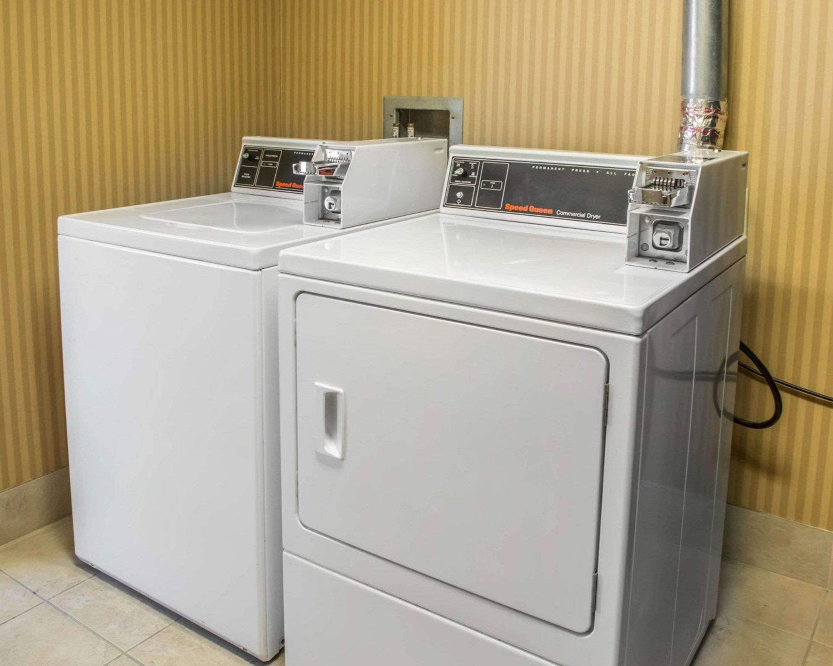 Two front-loading washing machines in a laundry room with a striped wall and tiled floor.