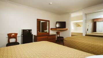 A hotel room with two beds, a desk with a computer, a TV, and a mirror.