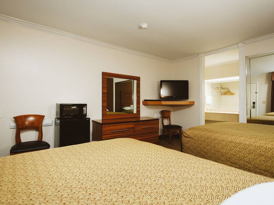 A hotel room with two beds, a desk with a computer, a TV, and a mirror.